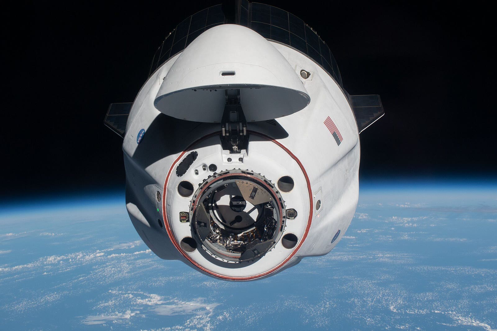 SpaceX's Crew Dragon Endeavour, nose cone open and docking port visible, approaching the International Space Station with Earth's blue horizon below