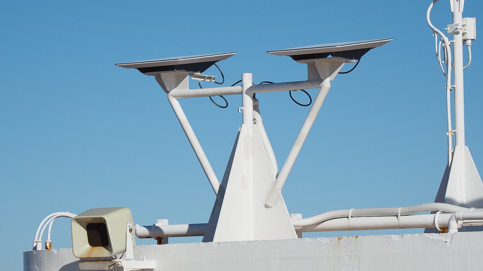 Two Starlink flat-panel dishes on a white mount against a clear blue sky
