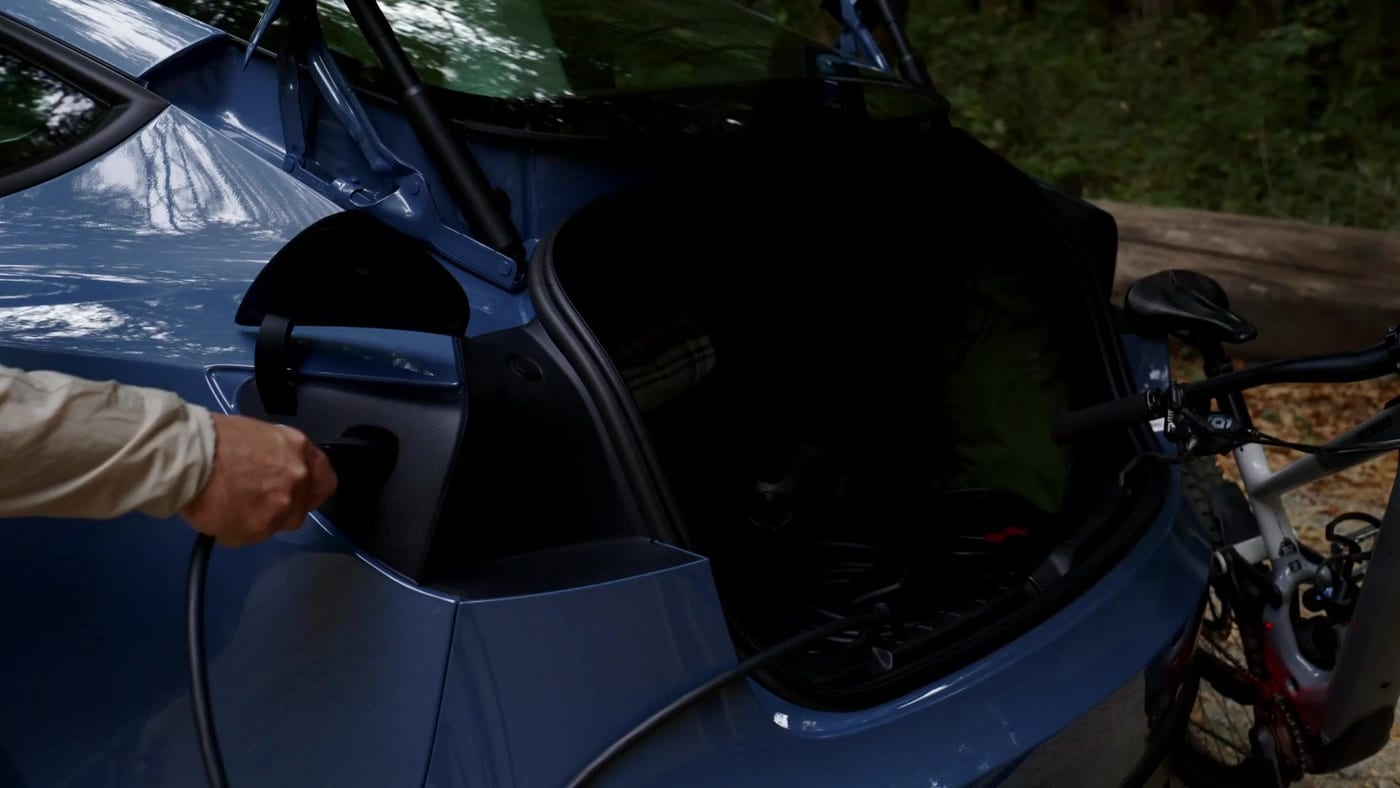A Tesla Mobile Connector being plugged into a blue Tesla’s charge port outdoors (still: Tesla North America video)