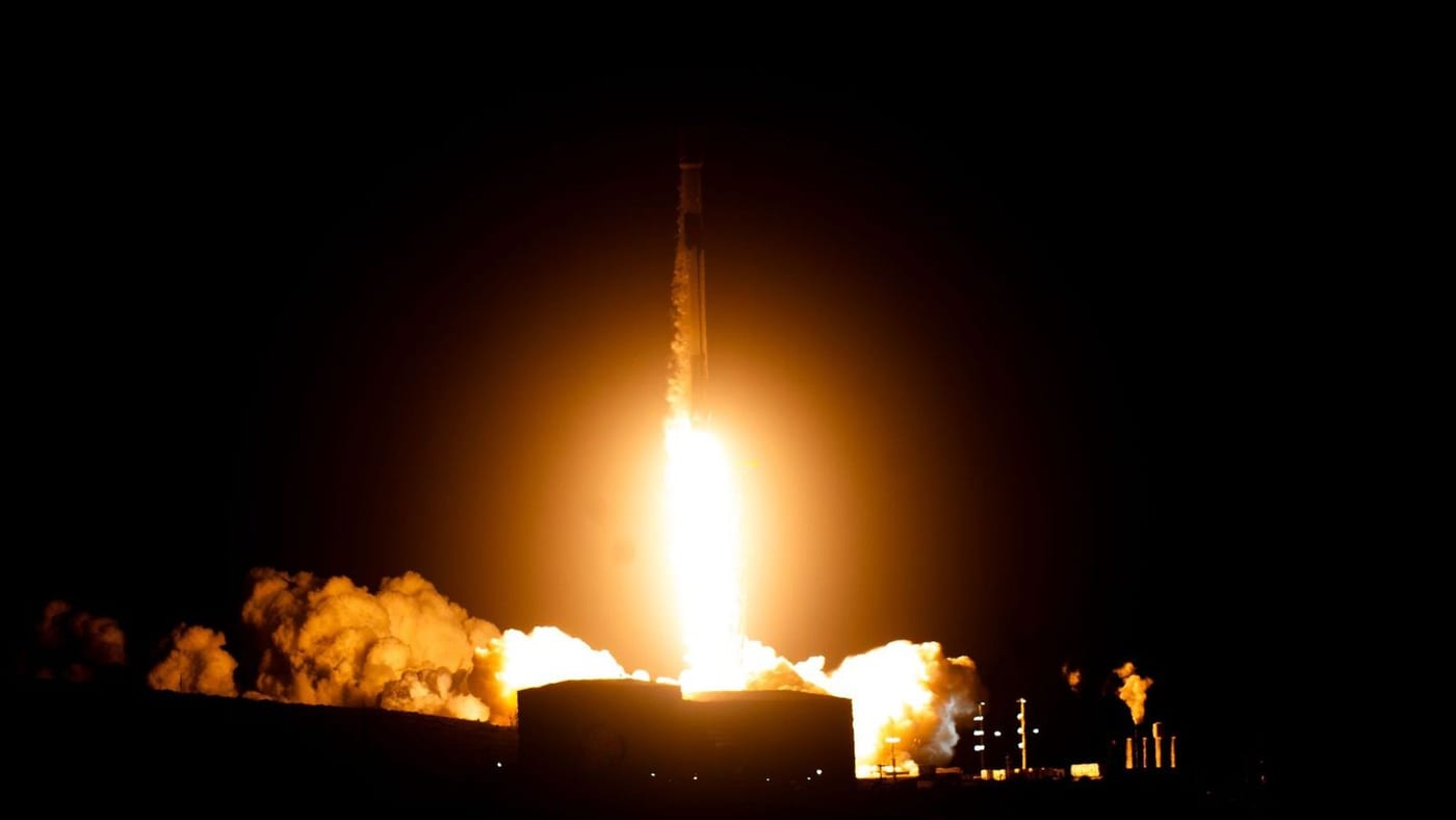 A Falcon 9 rocket lifts off at night from Space Launch Complex 4 East at Vandenberg, lighting up clouds of exhaust