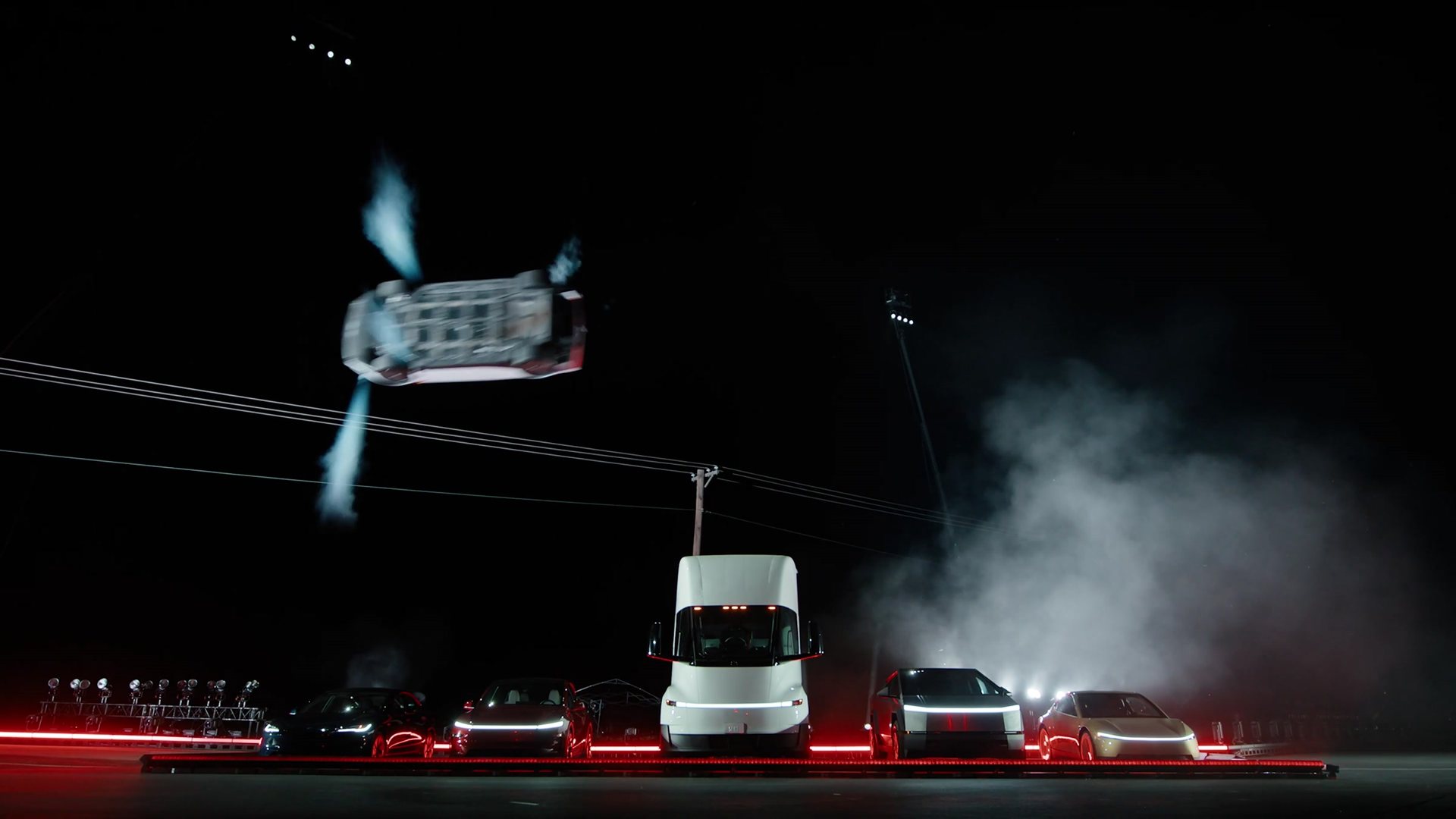 The Roadster airborne above a line of Teslas including a Semi