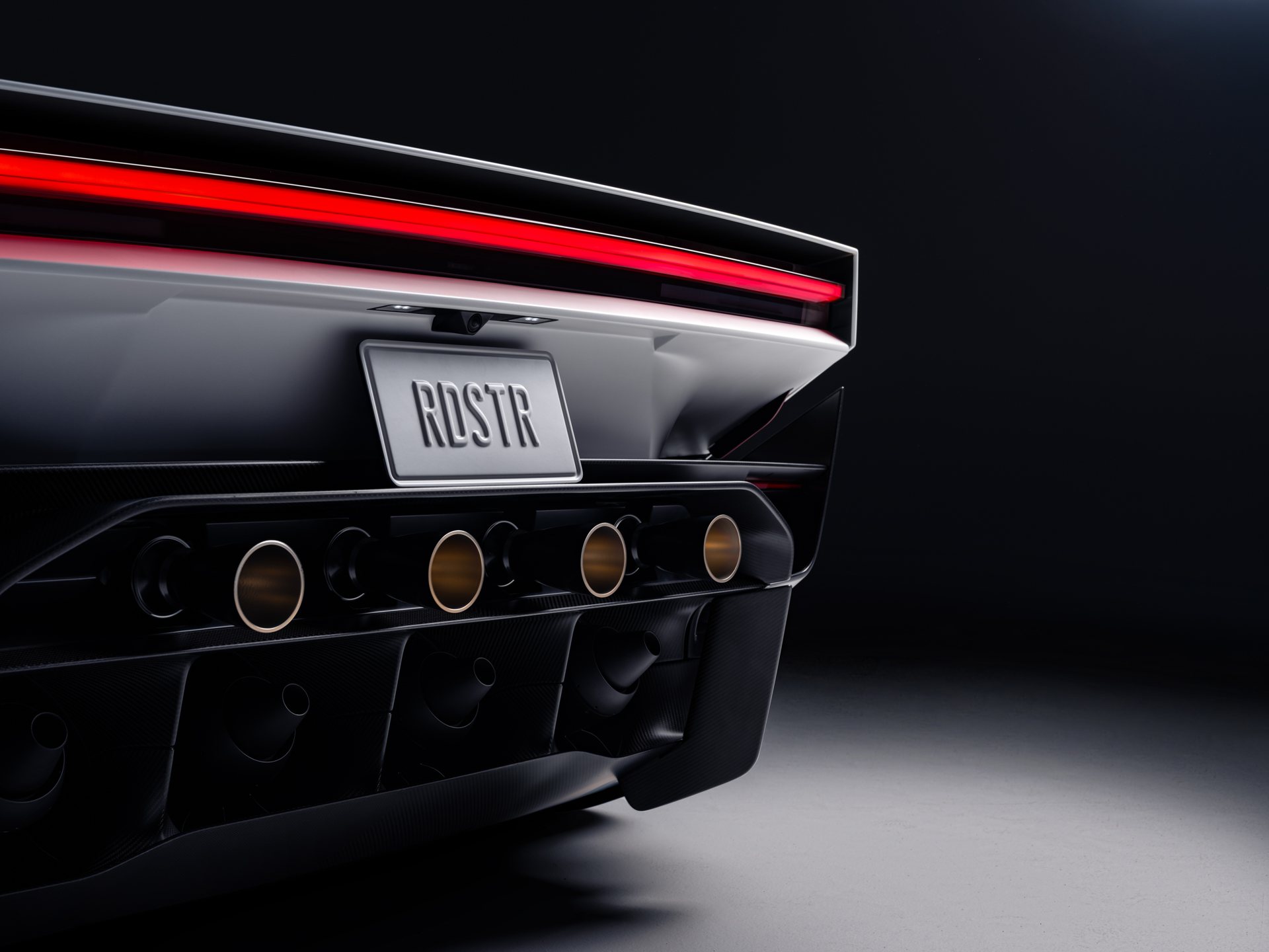 Close-up of the Roadster rear with a row of cold-gas thruster nozzles under the light bar and an RDSTR plate